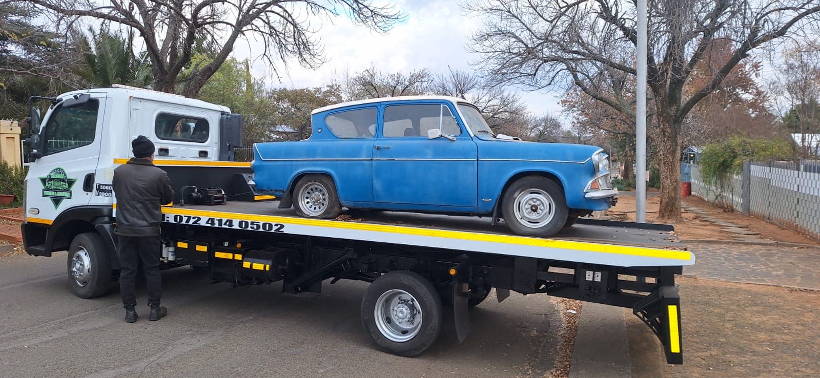Blue classic car loaded on a flatbed tow truck