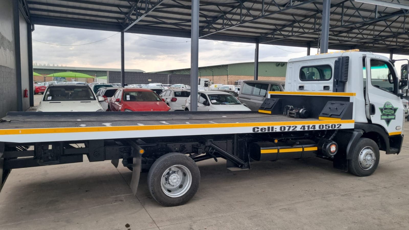 Bloem Towing flatbed truck parked under a covered area