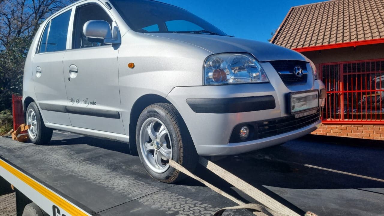 Silver hatchback secured on a flatbed tow truck
