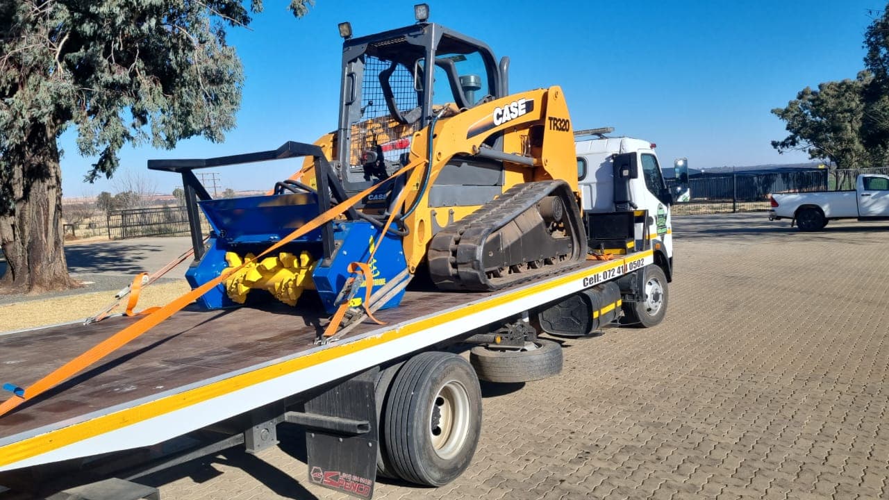 Skid steer loader secured on a flatbed tow truck